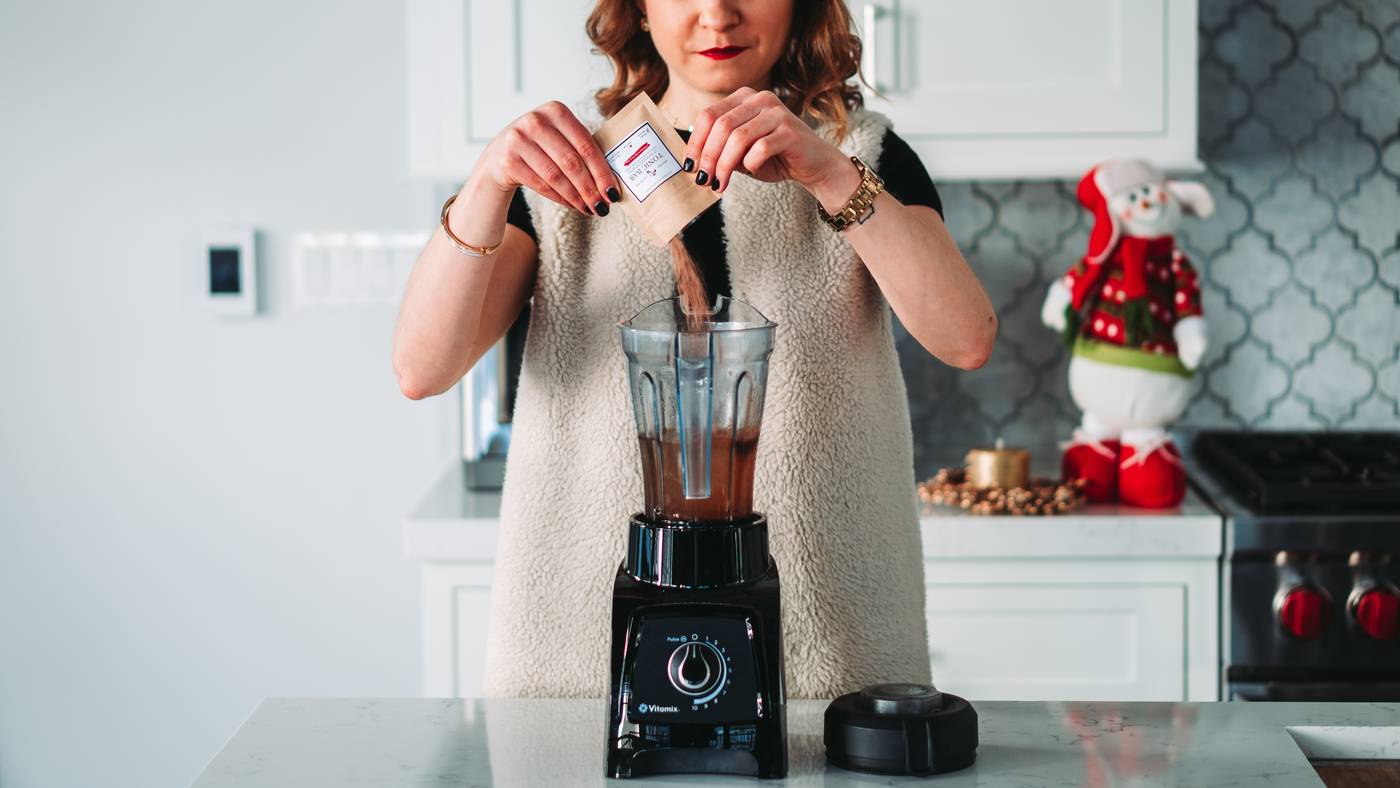 Woman filling blender in kitchen