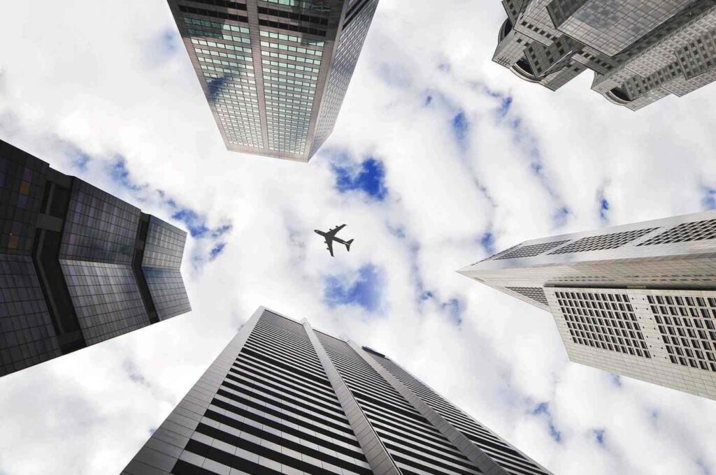 Airplane flying over four tall buildings