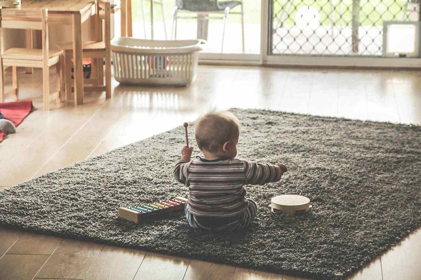 Bambino che suona lo xilofono e il tamburello sul tappeto