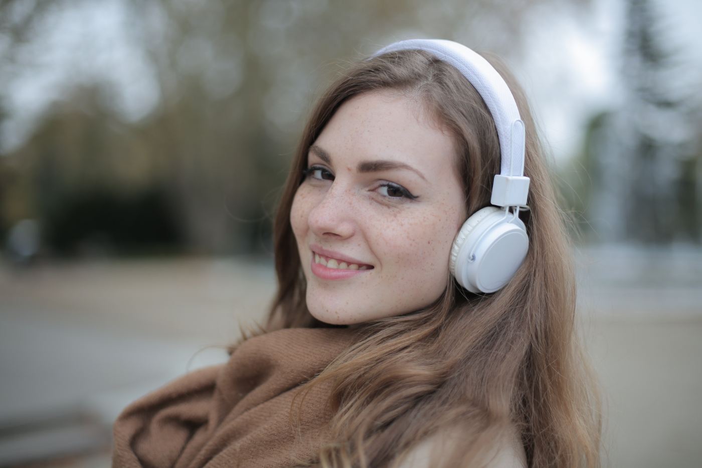 Young woman wearing headphones outdoors - Are noise-cancelling headphones safe?