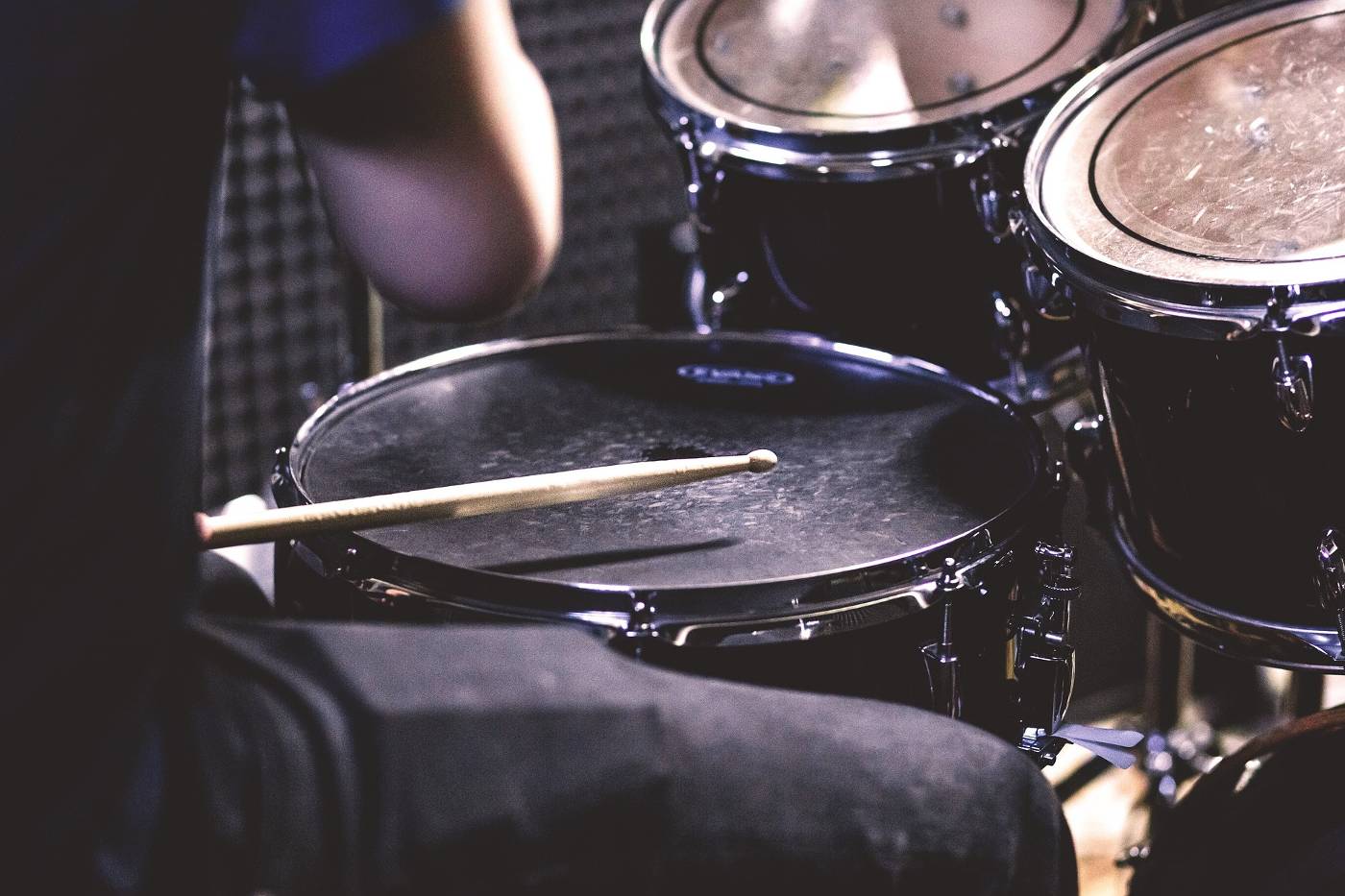 Person playing drums with soundproofing panels on wall - Complete Guide to Soundproofing for Drums